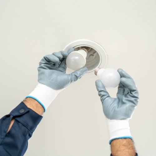 Electrician installing led light bulbs at home for power saving. Fixing changing the Light Inside apartment. Home service concept.